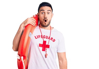 Cankurtaran üniforması giyen yakışıklı genç adam şamandırayı tutuyor. Korkmuş ve şaşkın bir şekilde ağzı açık, inançsız bir yüz. 