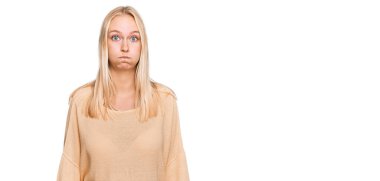 Sıradan kıyafetler giyen genç sarışın kız komik yüzlü yanakları şişiriyor. Havayla şişmiş ağız, çılgın bir ifade.. 