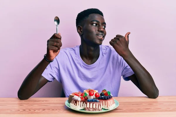 Jeune Homme Afro Américain Assis Sur Table Mangeant Des Gâteaux — Photo