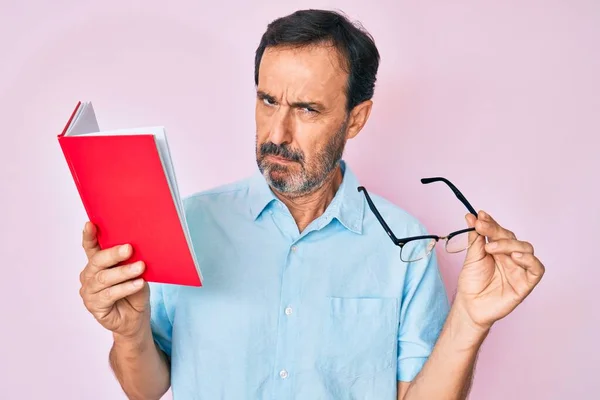 Medelåldern Hispanic Man Läsa Bok Hålla Glasögon Skeptisk Och Nervös — Stockfoto