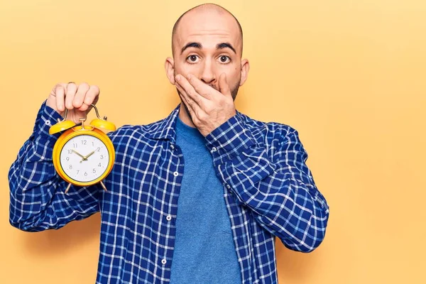 Young Handsome Bald Man Holding Alarm Clock Covering Mouth Hand — Stock Photo, Image