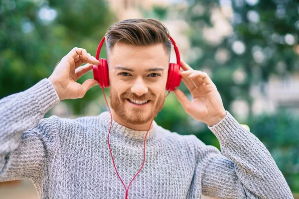 Joven Hombre Caucásico Sonriendo Feliz Escuchando Música Usando Auriculares Parque —  Fotos de Stock