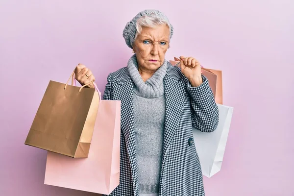 Senior Gråhårig Kvinna Håller Shoppingväskor Skeptisk Och Nervös Rynkar Pannan — Stockfoto