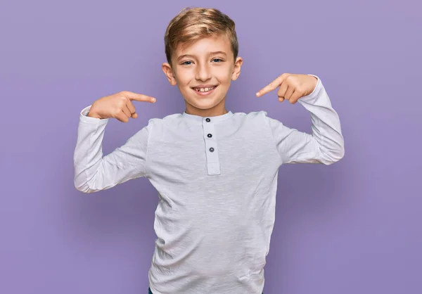 カジュアルな服を着ている小さな白人の少年は 陽気で笑顔で 指の歯と口を指差しています 歯の健康の概念 — ストック写真