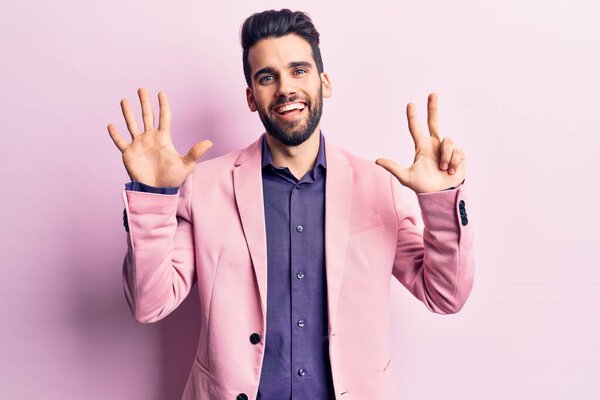 Young handsome man with beard wearing elegant jacket showing and pointing up with fingers number eight while smiling confident and happy. 