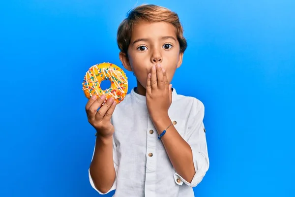 Adorable Niño Latino Sosteniendo Boca Cubierta Rosquilla Con Mano Sorprendido — Foto de Stock