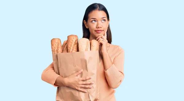Young Beautiful Latin Girl Holding Paper Bag Bread Serious Face — Stock Photo, Image