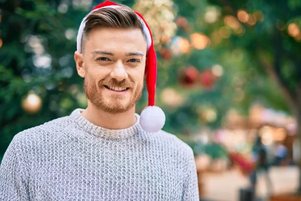 Νεαρός Καυκάσιος Άντρας Χαμογελάει Χαρούμενος Φορώντας Χριστουγεννιάτικο Καπέλο Στο Πάρκο — Φωτογραφία Αρχείου