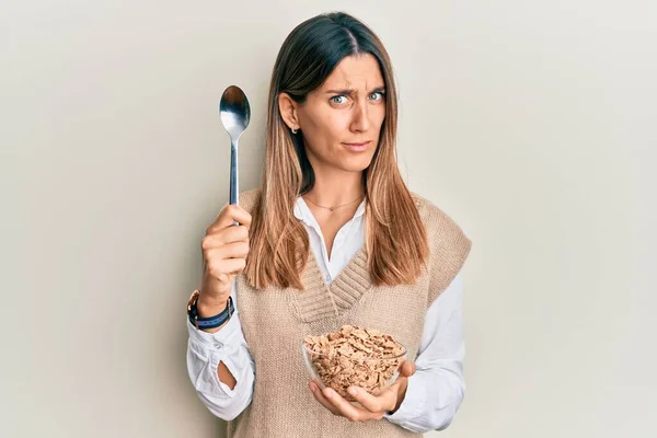 Mujer Joven Morena Comiendo Cereales Integrales Saludables Con Cuchara Escéptica — Foto de Stock
