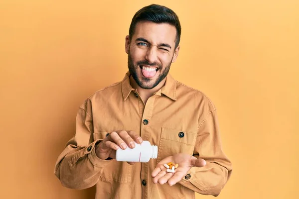 Молодий Іспаномовний Чоловік Тримає Таблетки Витираючи Язик Щасливим Кумедною Виразою — стокове фото