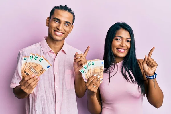 Pareja Latina Joven Sosteniendo Billetes Euros Sonriendo Feliz Señalando Con — Foto de Stock