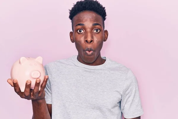 Jovem Afro Americano Segurando Porquinho Banco Assustado Espantado Com Boca — Fotografia de Stock