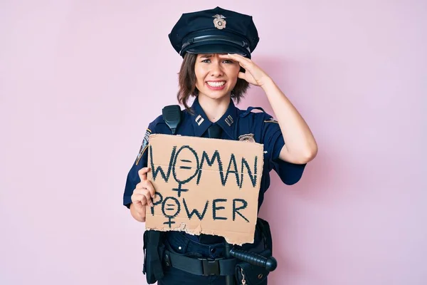 Young beautiful girl wearing police uniform holding woman power banner stressed and frustrated with hand on head, surprised and angry face