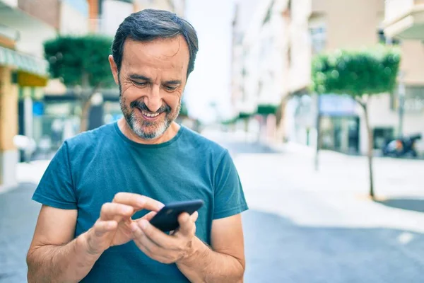 中年男人留着胡子 在户外用智能手机开心地笑着 — 图库照片