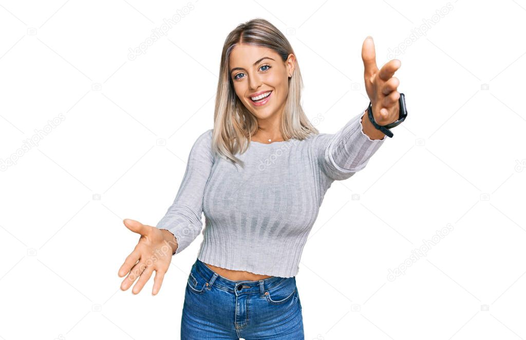 Beautiful blonde woman wearing casual clothes looking at the camera smiling with open arms for hug. cheerful expression embracing happiness. 