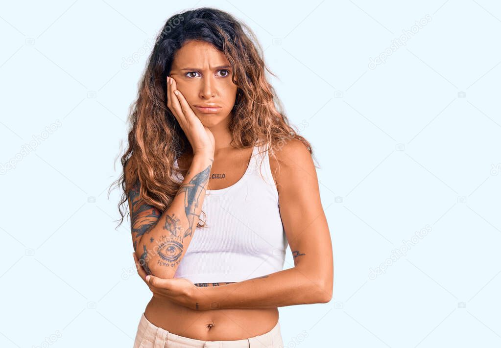 Young hispanic woman with tattoo wearing casual clothes thinking looking tired and bored with depression problems with crossed arms. 