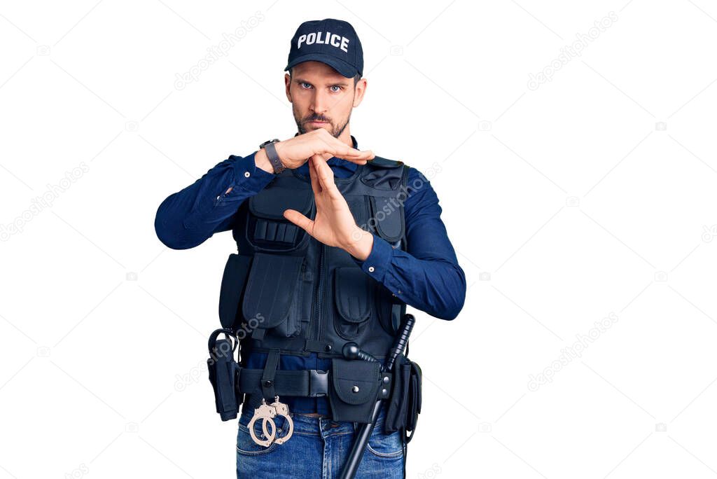 Young handsome man wearing police uniform doing time out gesture with hands, frustrated and serious face 