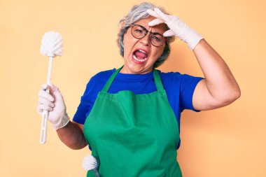 Önlük giyen son sınıf İspanyol kadın elinde fırçayla gergin ve hayal kırıklığına uğramış, şaşırmış ve sinirli bir yüz ifadesi var. 