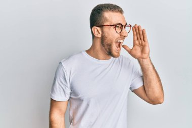 Günlük kıyafetler ve gözlük takmış genç beyaz bir adam el ve ağızla bağırıyor ve bağırıyordu. iletişim konsepti. 