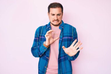 Gayri resmi giyinen genç yakışıklı adam tiksinti ifadesi, tiksinti ifadesi, tiksinti ve korku ifadesi takınıyor.. 