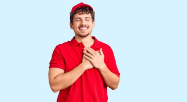 Kıvırcık saçlı, teslimat üniforması giyen, elleri göğsünde, gözleri kapalı ve yüzünde minnet ifadesi olan genç yakışıklı bir adam. sağlık kavramı. 