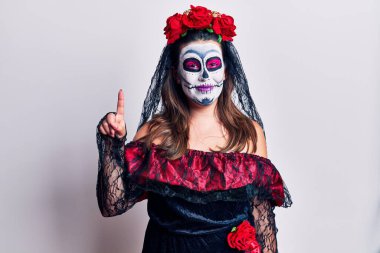 Genç bir kadın, ölü kostümünü beyazların üzerine giyip bir numaralı parmağıyla işaret ederken kendinden emin ve mutlu bir şekilde gülümsüyor.. 