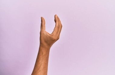 Pembe izole edilmiş arka plandaki beyaz adamın kolu ve eli. Görünmez bir şeyi alıp götürüyor. Parmakları yer gösteren bir nesneyi tutuyor. 