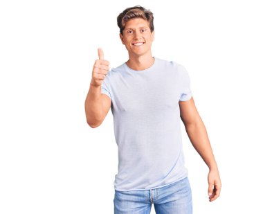 Gündelik kıyafetler giyen, mutlu ve pozitif gülümseyen, mükemmel ve onay işareti yapan genç yakışıklı bir adam. 