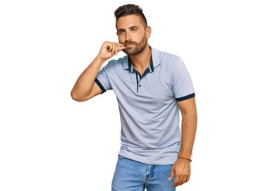 Sakallı, sıradan kıyafetler giyen, ağzı ve dudakları parmaklarıyla kapanan yakışıklı bir adam. gizli ve sessiz, tabu konuşması 