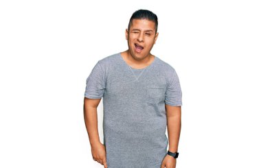 Gündelik kıyafetler giyen genç Latin adam kameraya seksi bir ifadeyle bakıyor, neşeli ve mutlu bir yüzle.. 