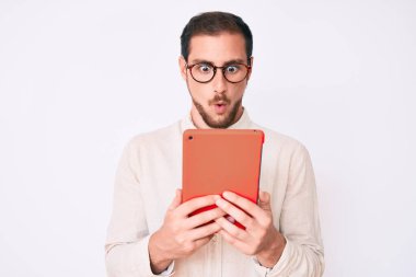 Genç yakışıklı adam dokunmatik ped kullanıyor. Korkmuş ve ağzı açık kalmış, şaşırmış ve şaşırmış. İnanmayan yüz. 