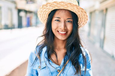 Genç, güzel Hintli kadın, yaz şapkası takıyor, gülümsüyor ve şehirde mutlu mesut yürüyor..