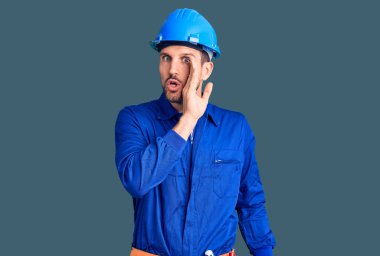 Genç yakışıklı bir adam işçi üniforması giyiyor ve elleri ağızda gizli dedikodular anlatıyor, kötü niyetli konuşmalar fısıldıyor. 