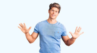 Genç ve yakışıklı bir adam günlük kıyafetler giyer ve 10 numarayı göstererek gülümserken kendinden emin ve mutluydu.. 