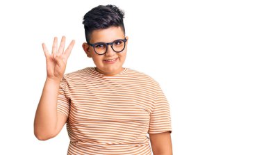 Küçük çocuk günlük kıyafetler ve gözlük takıyor. Dört numarayı gösteriyor ve işaret ediyor. Kendinden emin ve mutlu bir şekilde gülümsüyor.. 