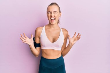 Güzel sarışın kadın spor giyer ve kol bandı takar. Deli gibi bağırır, bağırır, agresif bir ifade ve kollar havada bağırır. hüsran kavramı. 
