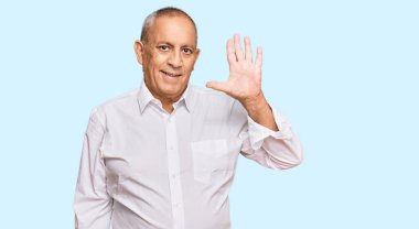 Zarif beyaz gömlek giyen yakışıklı son sınıf öğrencisi beş numarayı gösterip işaret ederken kendinden emin ve mutlu bir şekilde gülümsüyor.. 