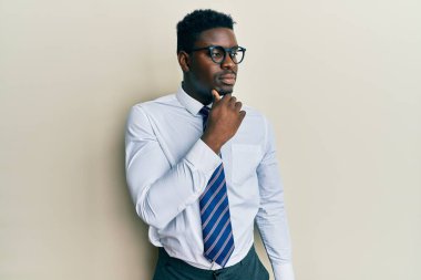Yakışıklı, gözlüklü, iş gömleği giyen, eli çenesinde kravat takan soru soran, düşünceli bir zenci. Düşünceli bir yüzle gülümsüyor. şüphe kavramı. 