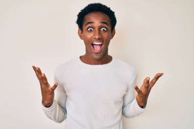 Sıradan bir kazak giyen Afrikalı yakışıklı adam zaferi mutlu bir gülümsemeyle ve kazanan ifadeyle kutluyor. 