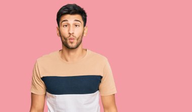 Gündelik kıyafetler giyen genç yakışıklı adam dudaklarıyla balık suratı yapıyor, çılgınca ve komik bir jest. Komik ifade. 