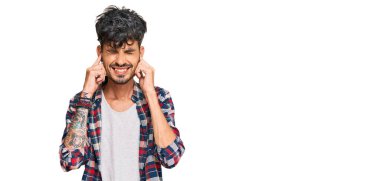 Gürültülü müzik sesi için günlük kıyafetler giyen genç İspanyol adam kulaklarını parmaklarıyla kapatıyor. sağır kavramı. 