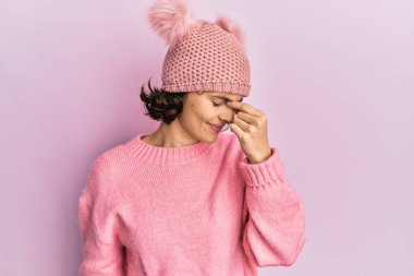 Şirin yün şapkalı esmer kadın yorgun burnu ve gözleri ovuşturup yorgun ve baş ağrısı çekiyor. Stres ve hüsran kavramı. 