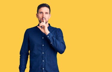 Gündelik tişört giyen genç yakışıklı dudakları parmaklarıyla sessiz olmak istiyor. sessizlik ve gizli konsept. 