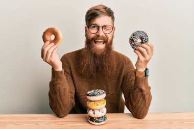 Genç İrlandalı kızıl adam kahvaltıda donut yiyor. Kameraya bakıyor. Seksi bir ifadeyle, neşeli ve mutlu bir yüzle.. 
