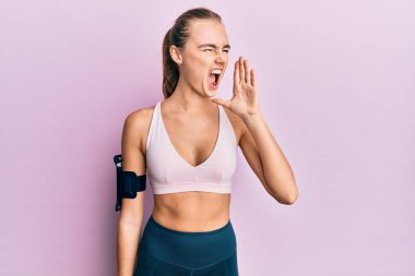 Spor kıyafetleri ve kol bandı takan güzel sarışın kadın el ele verip bağırıyor. iletişim konsepti. 