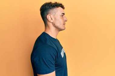 Gönüllü tişört giyen Latin kökenli genç bir adam. Taraf arıyor, profil pozu veriyor, doğal bir yüz ifadesi ve kendine güvenen bir gülümsemeyle.. 