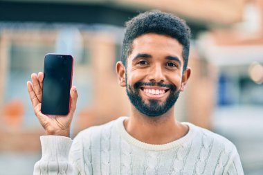 Genç Afrikalı Amerikalı adam gülümsüyor. Şehre akıllı telefon gösterdiği için mutlu..