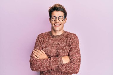 Sıradan süveter giyen ve kollarını kavuşturup kameraya gülümseyen yakışıklı beyaz bir adam. pozitif kişi. 