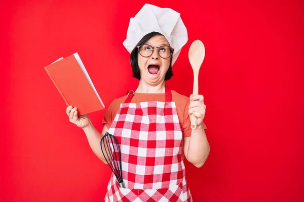 Brünette Frau Mit Syndrom Trägt Professionelle Bäckerschürze Kochrezeptbuch Lesen Wütend — Stockfoto