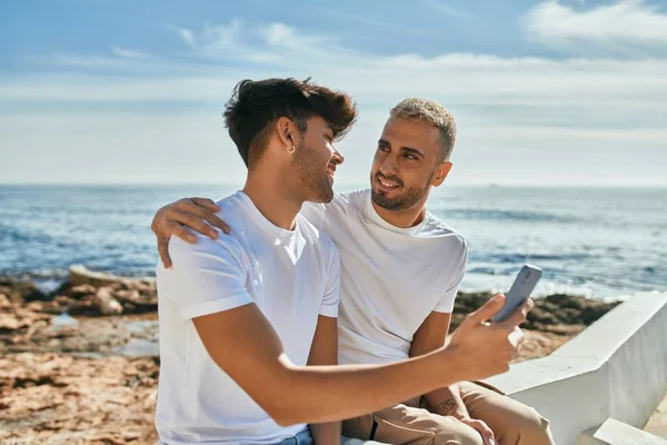 Genç Eşcinsel Çift Sahilde Akıllı Telefon Kullanarak Mutlu Bir Şekilde — Stok fotoğraf